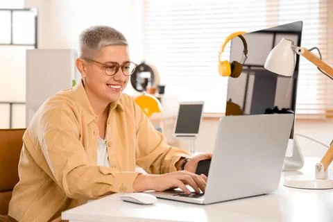 Female programmer working with laptop at desk in office Stock Photos