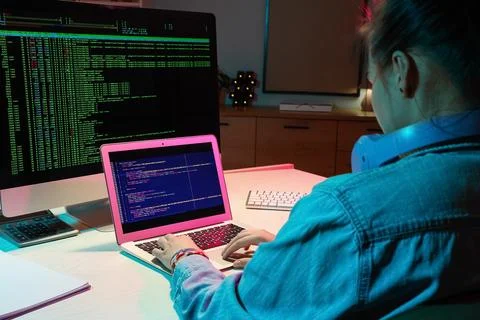 Female programmer working with laptop in office at night, back view Stock Photos