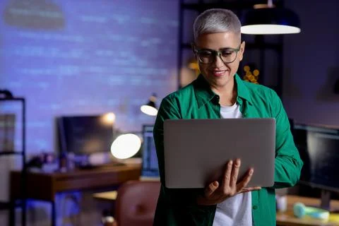 Female programmer working with laptop in office at night Stock-Fotos