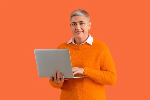 Female programmer working with laptop on orange background Stock Photos