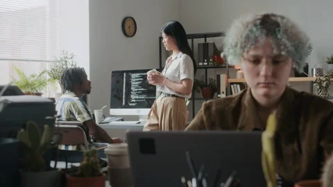 Female Programmer Working on Laptop while Colleagues Chatting in Office Stock-Footage 306210149
