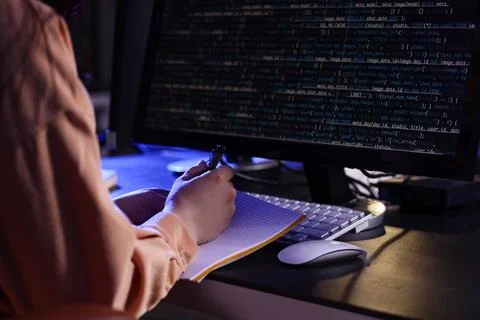 Female programmer working with notebook and computer in dark office at night, 스톡 사진