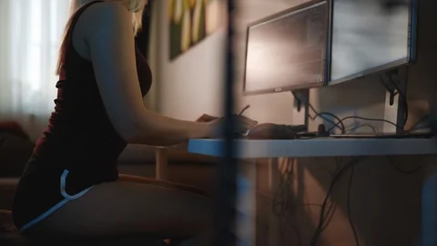 Female programmer writes code looking at two monitors at home Stock Footage 128174246