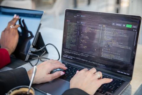 Female programmer writes some code and drinks coffee while sitting near her.. Stockfoto's