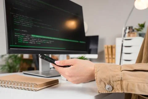 Female programmer's hand with mobile phone at table in office, closeup 스톡 사진