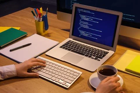 Female programmer's hands with cup of coffee working in office at night Stock Photos