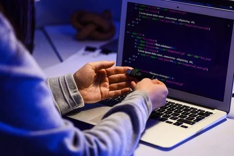 Female programmer's hands with USB flash drive and laptop on desk in office a Stock-Fotos