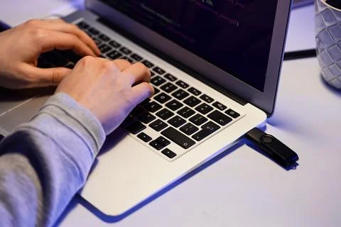 Female programmer's hands using laptop with USB flash drive on desk in office 스톡 사진