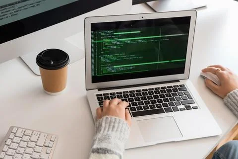 Female programmer's hands working with laptop at desk in office Stock Photos
