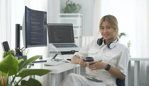 Female programmers sitting front of laptop and large curved computer monito.. Foto stock