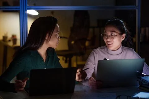 Female Programmers At Work In Evening Stock-Fotos