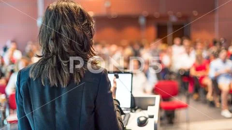 Female public speaker giving talk at Business Event. Stock Photos