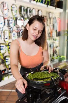 Female pulling strings to the racket on machine 스톡 사진