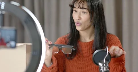 Female pulling sunglasses from pouch, inspecting lenses, showing to phone in Stock-Footage 345607690