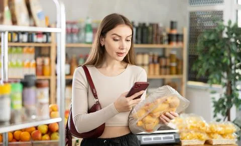 Female purchaser scanning QR code or barcode of chicken thighs in shop Stock Photos