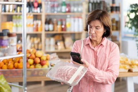 Female purchaser scanning QR code or barcode of pork fillet in shop Stock Photos