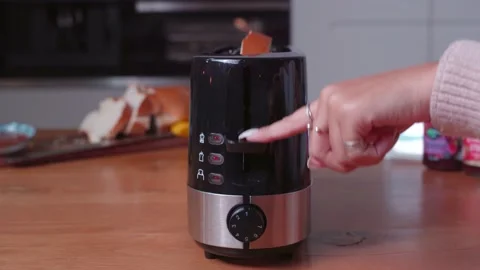 Female putting slice of bread in toaster and pushing down power handle to Stock Footage 237978702