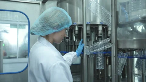 Female quality control worker inspecting water bottle on production line Stock Footage 254457713