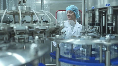 Female quality control worker inspecting water bottle on production line Stock Footage 254460151