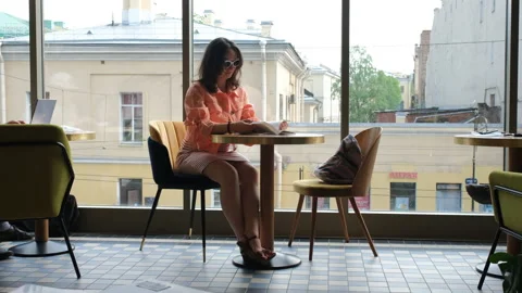 Female Reading Book while Sitting in Cafeteria Vídeos de archivo 156197733