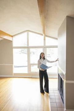 Female realtor with folder inspecting empty living room Foto stock