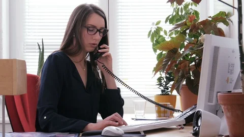Female receptionist working on computer and talking on phone in call center Stock Footage 87149396
