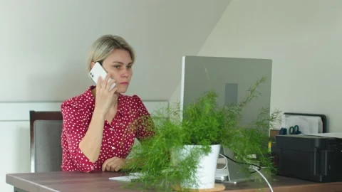 Female in red working desk computer indoor use mobile phone sit table look Stock Footage 235733664