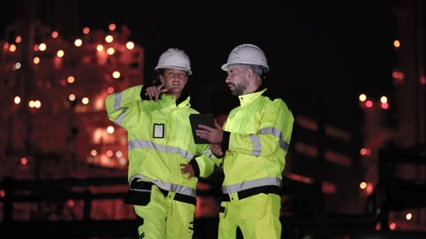 Female refinery engineer gestures during tablet discussion beside technician Stock Footage 338425674