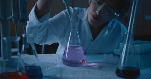 Female research scientist adding liquid to a conical flask,dolly in,slow motion Stock Footage 121135824