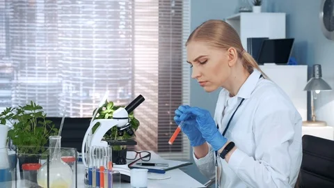 Female research scientist dropping sample on microscope slide and examining it Stock Footage 115245662