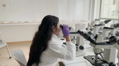 Female research scientist looking at samples under microscope Video stock 255903278