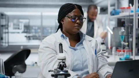 Female researcher brainstorms in laboratory, using laptop software Stock Photos