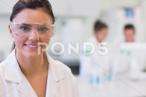 Female researcher with colleagues in background at lab Stock Photos