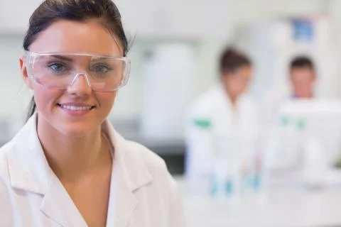 Female researcher with colleagues in background at lab Stock Photos