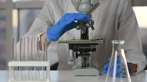 Female researcher looking at sample through microscope in laboratory Stock Footage 143328108