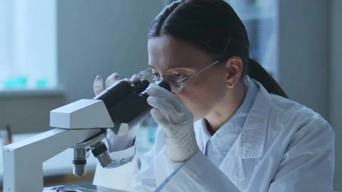 Female Researcher Looking through Microscope in Scientific Laboratory 库存影片 337320442