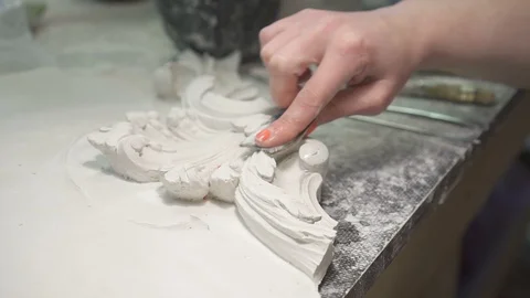 Female restorer is working with plaster decorations, sitting at table in Stock Footage 121390102