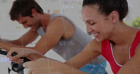 Female rider checking console and upping effort, male rider mirroring, fitness Stock-Footage 330981150