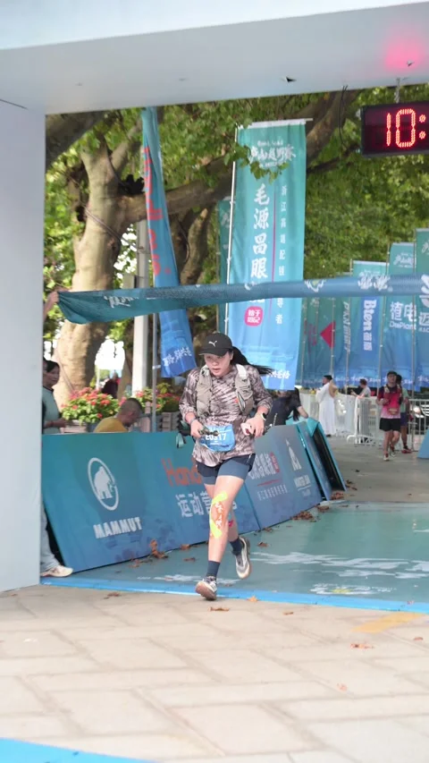 Female Runner Breaking Finish Tape under Race Arch, Lushan Stock Footage 346717075