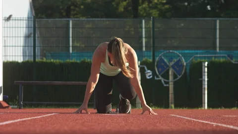 Female runner in a crouching start position for the sprint, front view Stock Footage 245754609