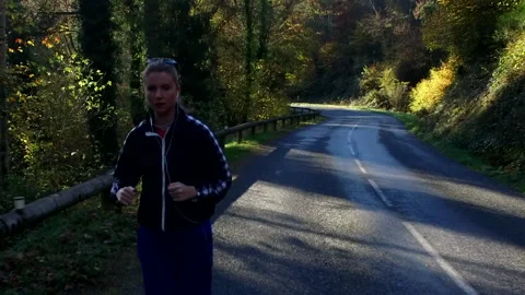 Female Runner on Forrest Road - Front Shot Stock Footage 142887124