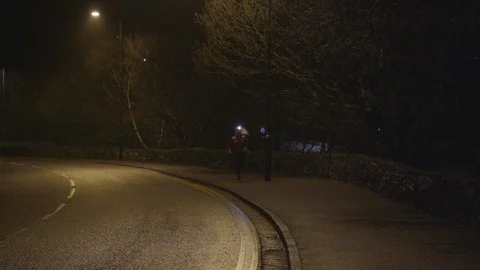 Female runner with head torch jogging on sidewalk at night Stock Footage 113005855