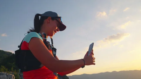 Female Runner with Hydration Pack Taking Sunset Selfie in Mountain Scenery 库存影片 314202448