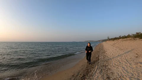 Female runner jogging on the sandy beach at sunset Stock Footage 107905929