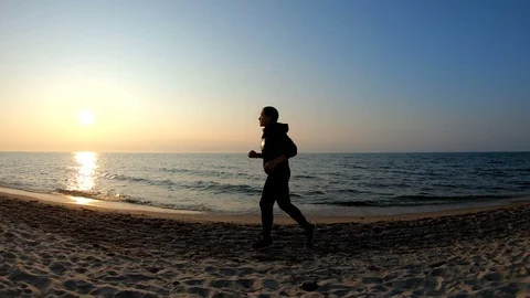 Female runner jogging on the sandy beach at sunset Stock Footage 107906736