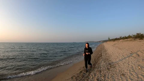 Female runner jogging on the sandy beach at sunset Stock Footage 107907445