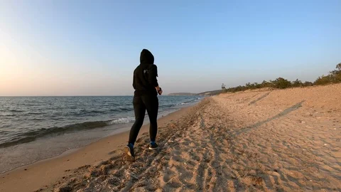 Female runner jogging on the sandy beach at sunset Stock Footage 107907714