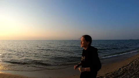 Female runner jogging on the sandy beach at sunset Stock Footage 107907788