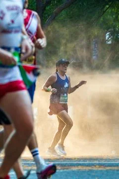 Female runner jogs through misting spray at Peachtree Road Race Stock Photos