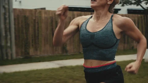 Female runner passing discarded paper cup along quiet fenced path Stock Footage 339621501